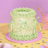 Vintage Cake - Single Colour with pale green Swiss Meringue icing, ribbons, and intricate hand-piped decoration by Crumbs & Doilies